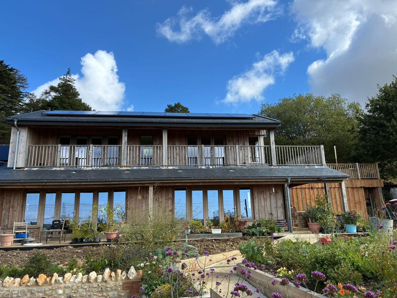 Finished timber clad house with balcony and roof mounted solar panels