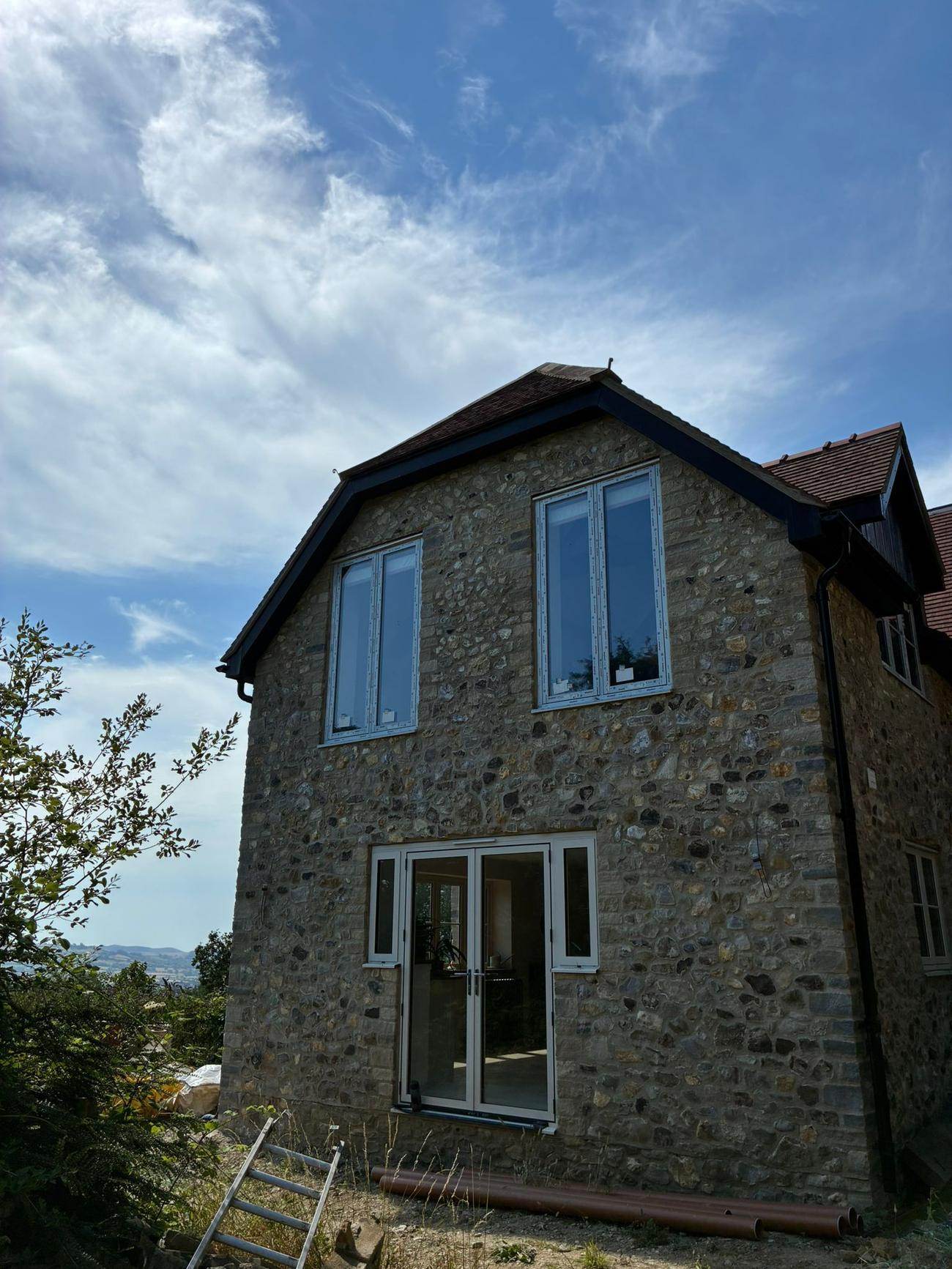 Rubble stone gable with French doors and a clay tile roof