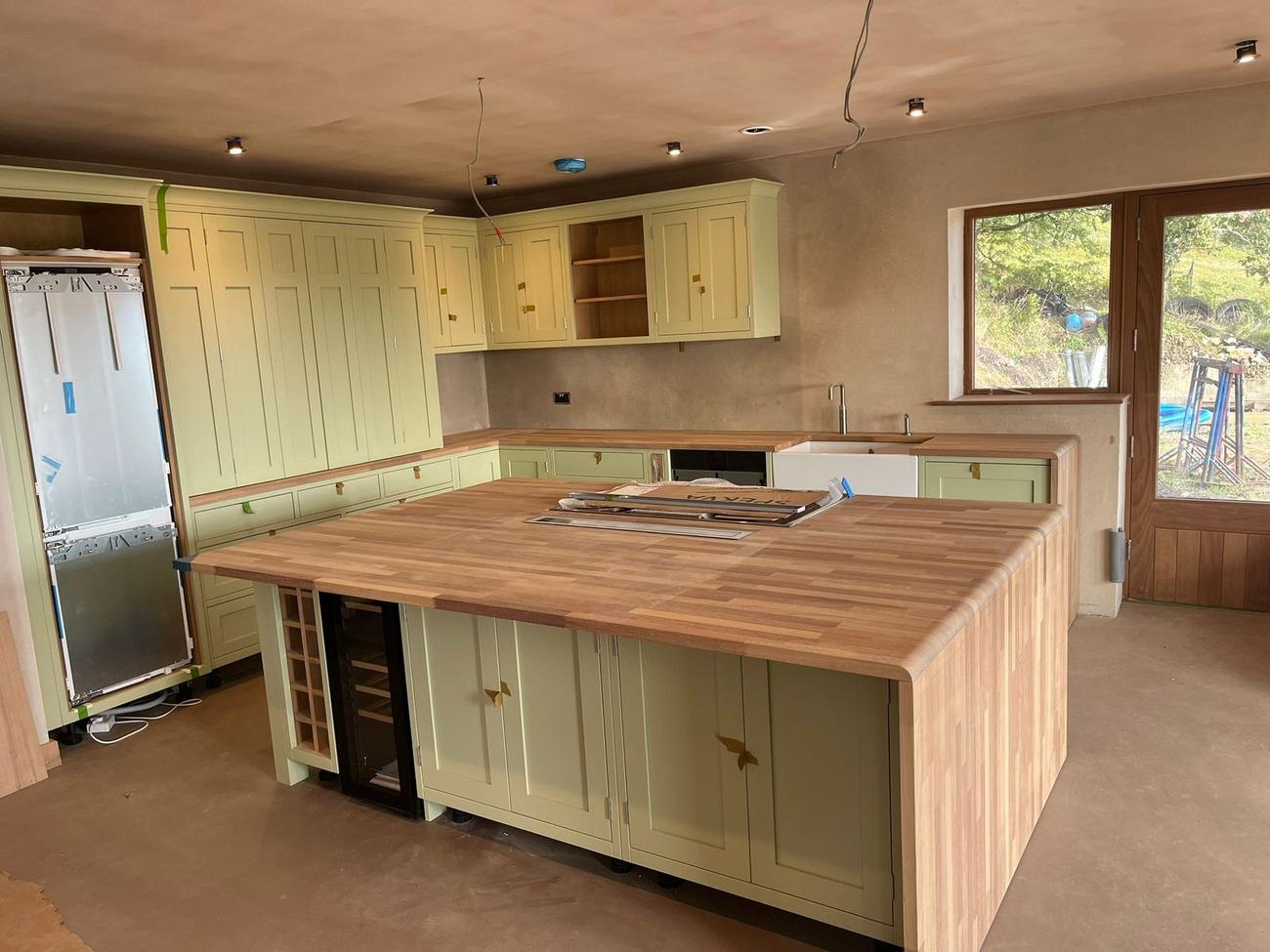 Sage green shaker kitchen with a solid oak island and butler sink