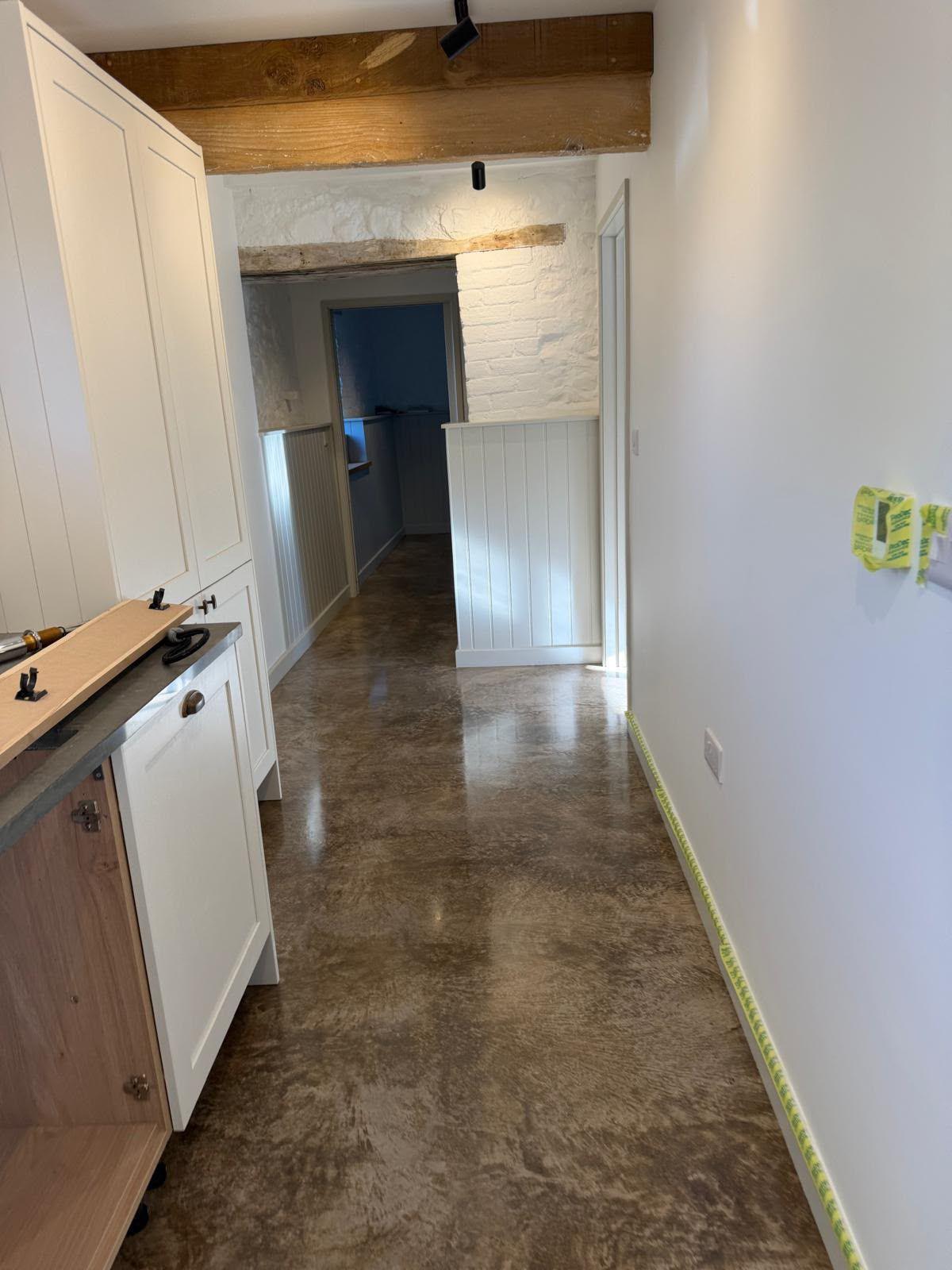 Plastered hallway with an exposed beam and a polished concrete floor