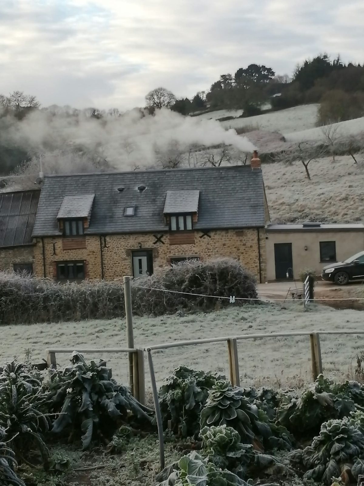 Converted stone barn with slate roof and rooflight on a frosty morning, West Dorset