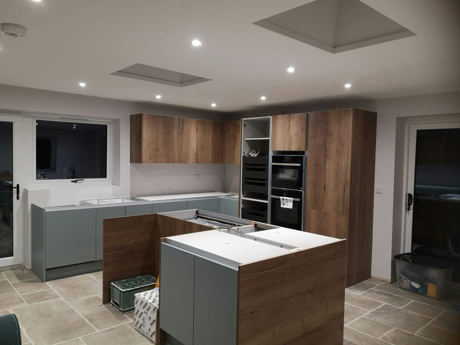 Fitted kitchen with oak and sage green island and recessed ceiling lights